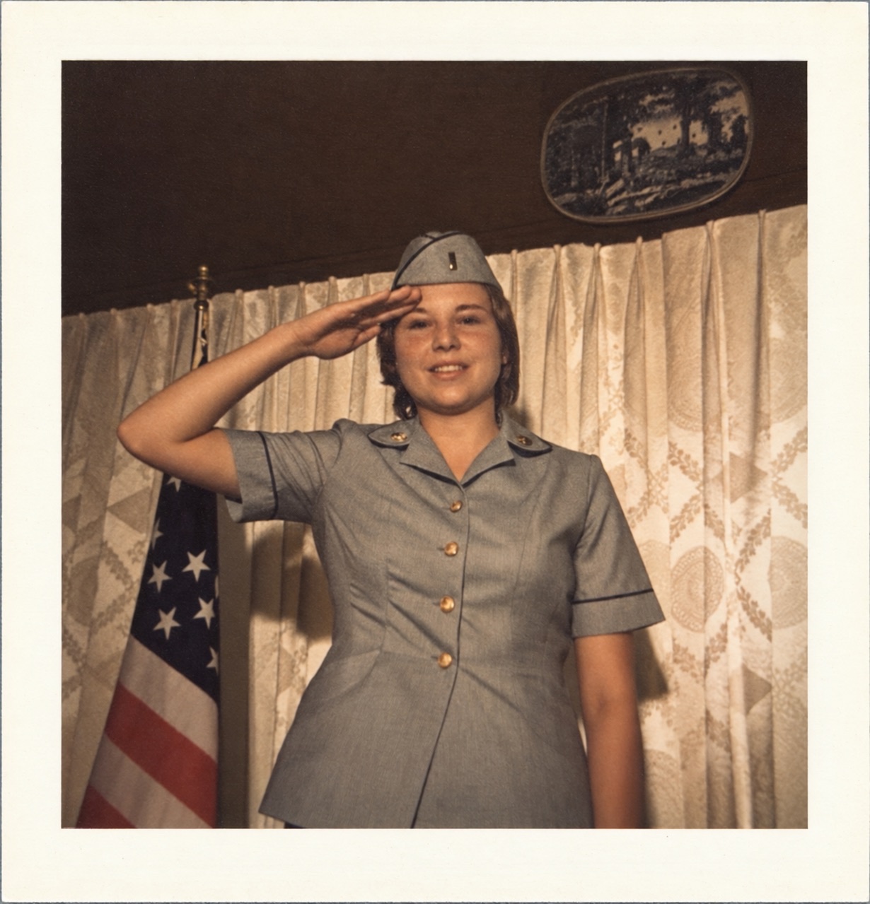 Betty in Army uniform saluting beside the American flag in 1973
