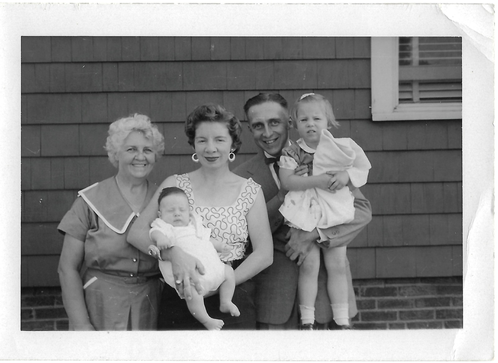 Family and children beside a house