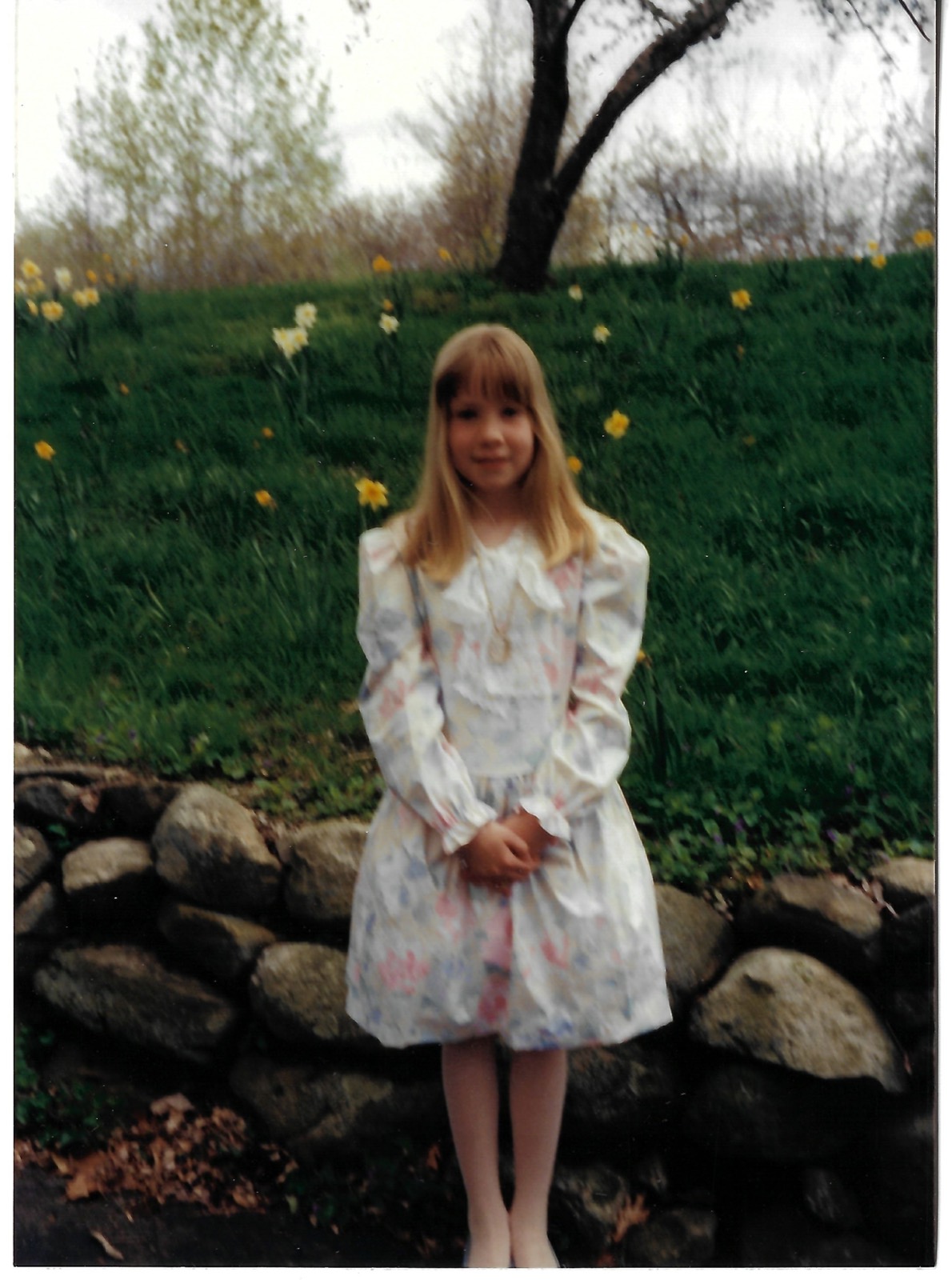 Eileen in a floral dress by a stone wall