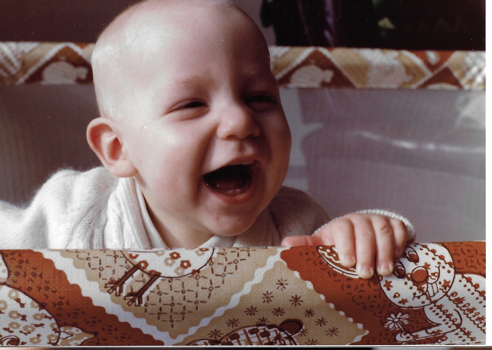 Baby Dave smiling in a playpen