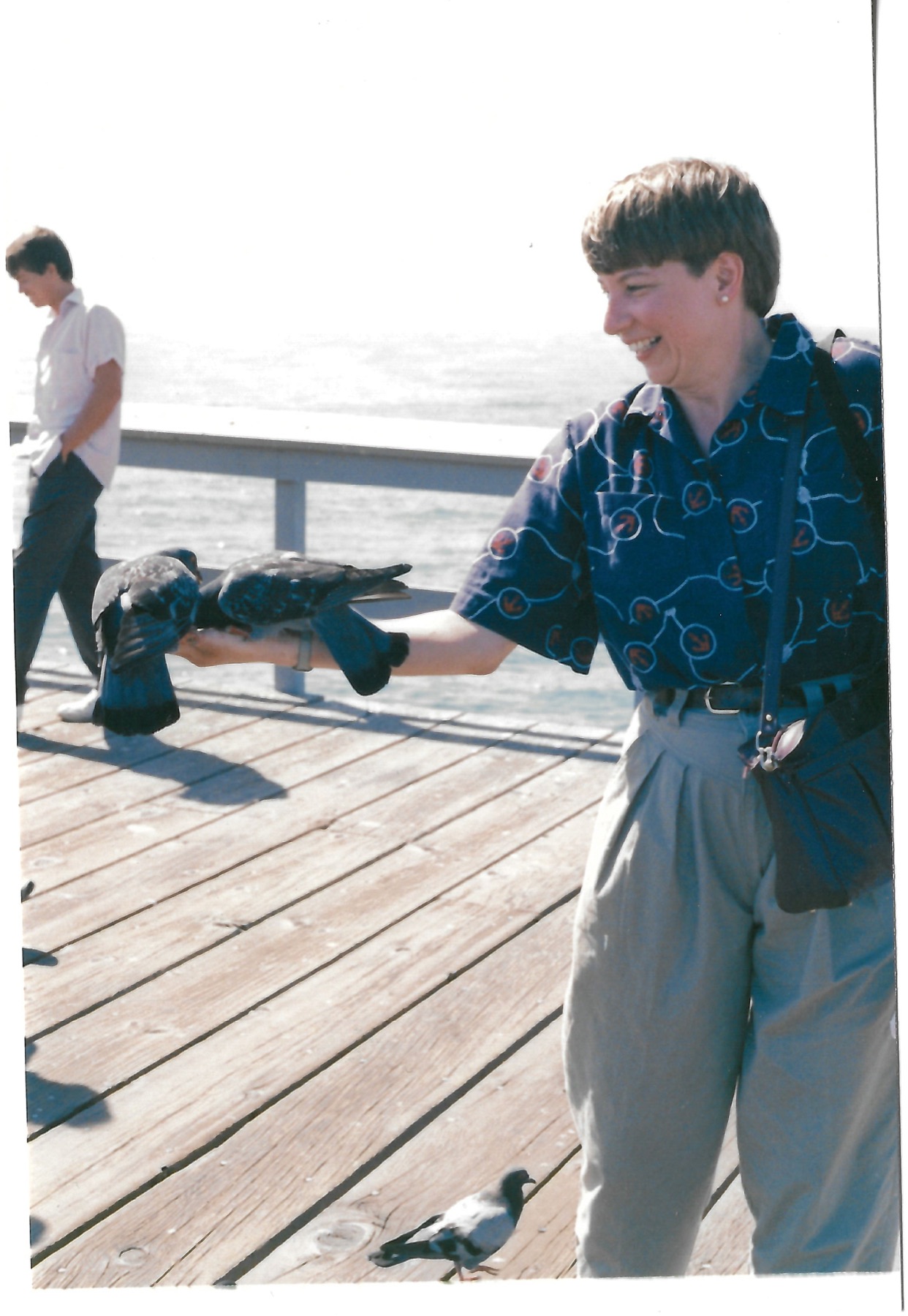 Betty feeding pigeons on a pier; date not confirmed