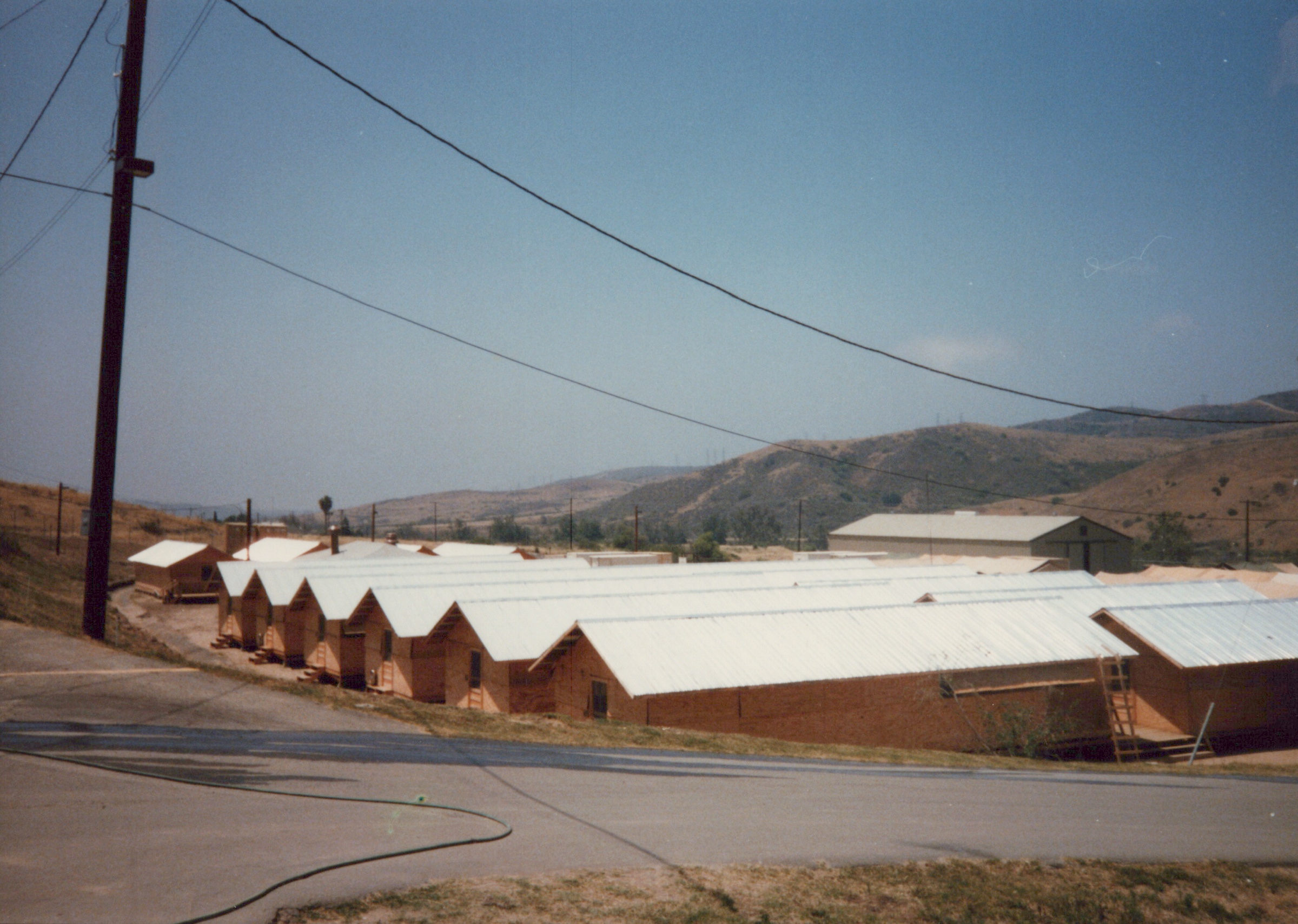 Fleet Hospital 007: Rows of tent roofs seen from above with hills behind them.