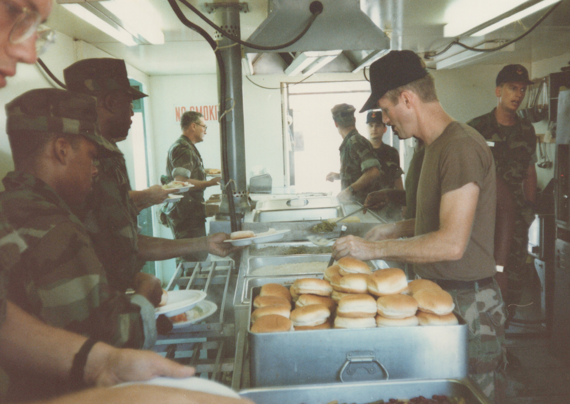 Fleet Hospital 007: Food-service personnel serve a line of meals in a field kitchen.