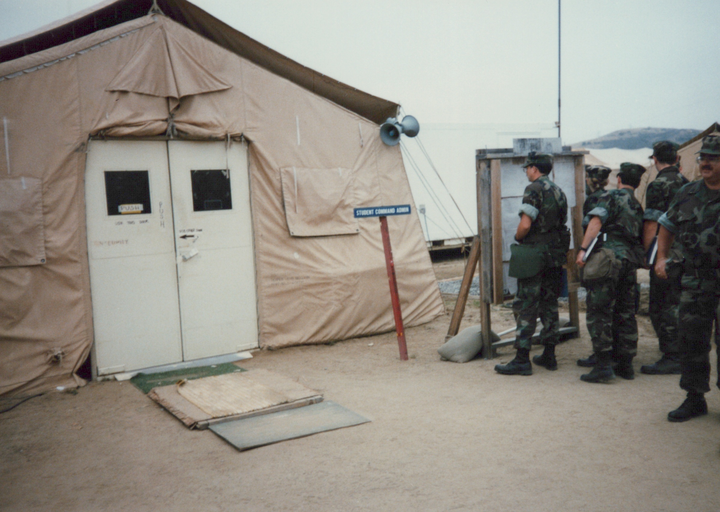 Fleet Hospital 007: People stand outside the doors of a tented building.