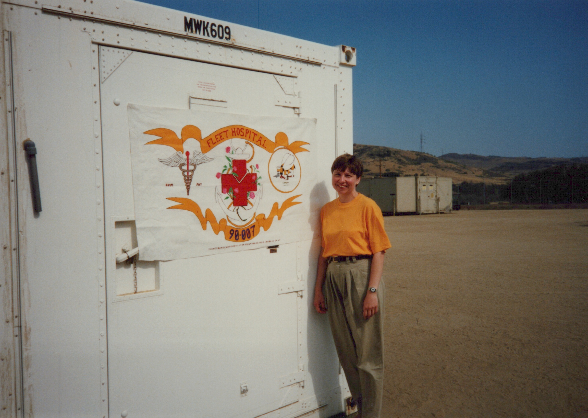 Fleet Hospital 007: Person beside Fleet Hospital 90-007 emblem on a storage unit.